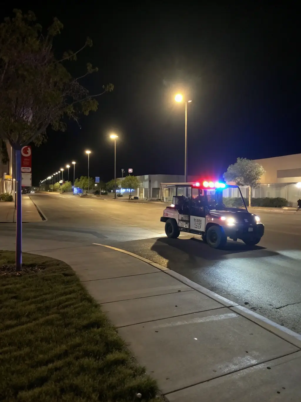 A marked security vehicle patrolling a commercial parking lot at night, deterring criminal activity through visible patrols.